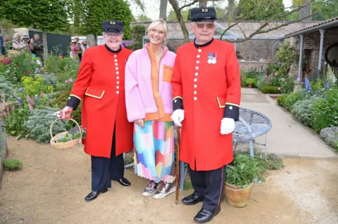 REX/Shutterstock Jo Wiley poses for a photograph with two Chelsea Pensioners at the RHS Chelsea Flower Show