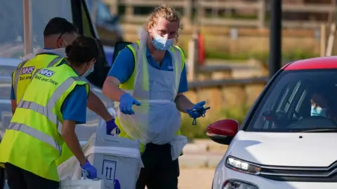 Getty Images Staff take testing kits from a member of the public at a mobile testing facility in Kirkleatham