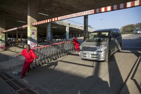 Kerstin Hacker Shopping centre workers return empty trolleys from the car park