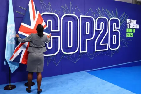 Getty Images A summit organiser adjusts flags before the arrival of leaders for the COP26 UN Climate Summit in Glasgow on 1 November 2021