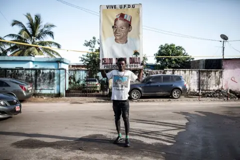  John Wessels / AFP / Getty Images A man holds up a placard in support of presidential candidate Cellou Dalein Diallo