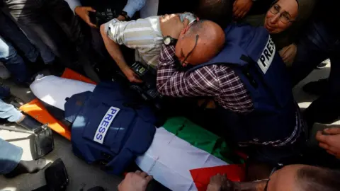 Reuters Journalists react next to the body of Al Jazeera correspondent Shireen Abu Aqla, who was shot dead during an Israeli raid in the occupied West Bank city of Jenin (11 May 2022)