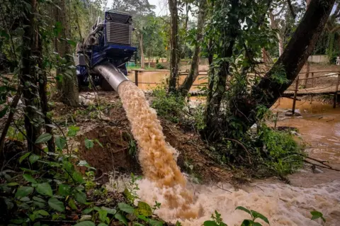 Getty Images Water is pumped out of Tham Luang Nang Non cave into a lake on the foot of Doi Nang Non mountain range