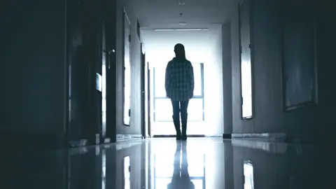 Getty Images Silhouette of young woman in what looks like a dark hospital ward