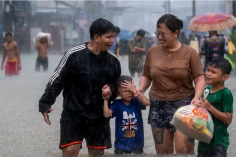 Reuters People wade through a flooded road, due to monsoon rains and typhoon Doksuri, in Balagtas, Bulacan province, Philippines, July 29, 2023