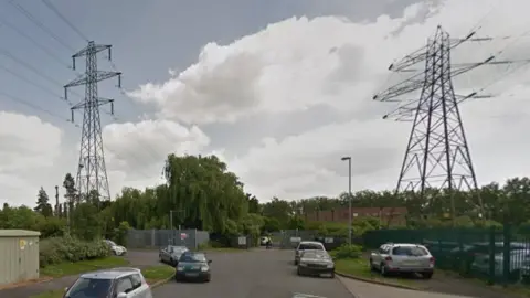 Google End of a road on a business park, showing grass and trees with electricity pylons