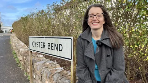 Emma sat by the Oyster Bend road sign