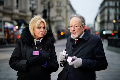 Aaron Chown / PA Media Dame Joanna Lumley handing out memorial candles at Piccadilly Circus, central London, alongside Martin Stern, a survivor of the Holocaust
