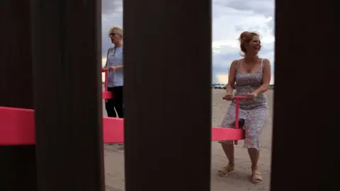 AFP A woman plays on the installation on the Mexican border with the US