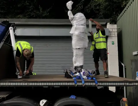 Hassan Akkad Two men unloading the new statue from a lorry