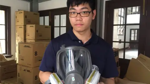 BBC Alex Ko holding a gas mask in a church storage room