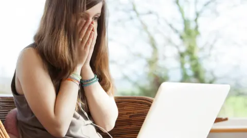 Girl covering face after looking at laptop