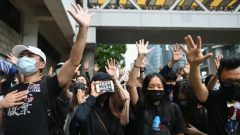 Getty Images Masked protesters gesture to symbolise their five demands outside the High Court premises.