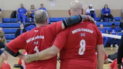 Mr Cresswell standing arm in arm with a teammate at the seated volleyball court at the US Air Force Warrior Games Trials where he represented Team UK in February