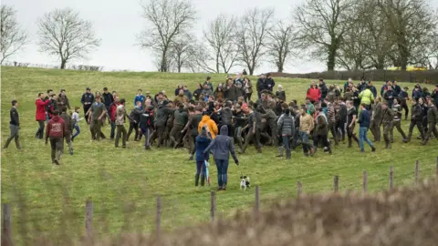 PA Competitors enter a field with the bottle