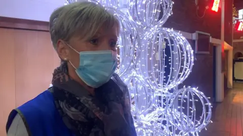 A lady standing in front of a glowing Christmas tree