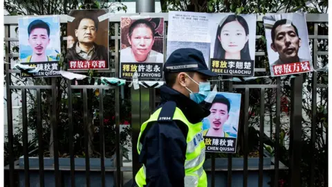 Getty Images A Hong Kong police officer walks past images of detained activists