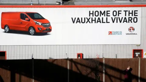 Reuters A person walks past a sign on Vauxhall's plant in Luton, Britain, March 6, 2017.