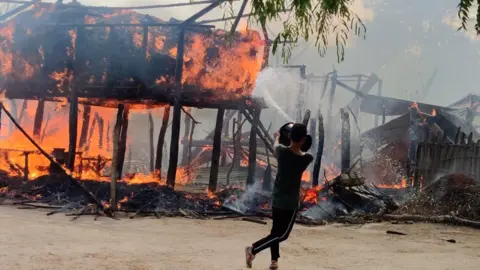 BBC A man tries to put out a fire