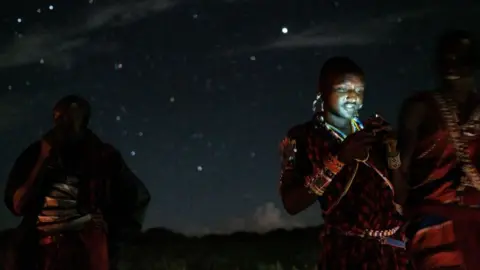 Getty Images A Maasai warrior uses his phone after dark after a sporting event near Kenya's border with Tanzania.