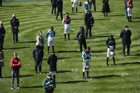 PA Media Racegoers and riders observe a two-minute silence for the late Prince Philip whilst social distancing