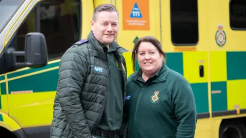 London Ambulance Service Angie and Steve Mills stood in front of an ambulance