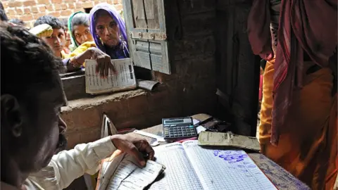 Getty Images Indian men and women line up outside the Fair Price Shop with their ration cards to receive portions of wheat, sugar, kerosene and rice from the government in Jhabua, Madhya Pradesh, India, on July 16, 2010.