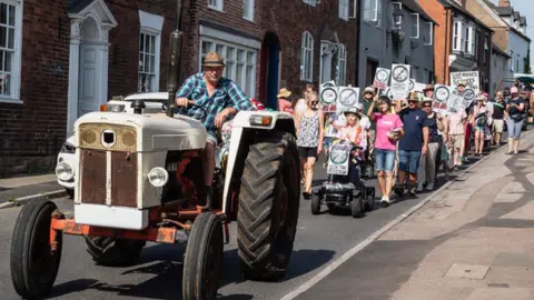 Future Newent A tractor leading a group of protestors down a road