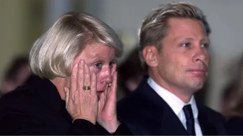 Pacemaker Barbara Stephenson. with her husband, wiping tears from her eyes during a Belfast church service for 9/11 victims