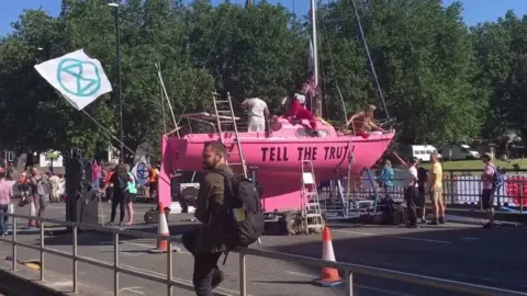 Extinction Rebellion protesters with a pink boat blocking Bristol Bridge