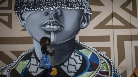 EPA A woman walks past an art mural.