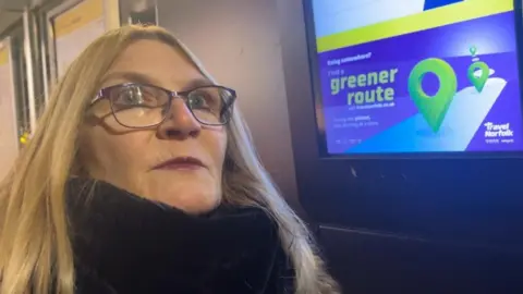 Andrew Turner/BBC Julie Roberts looks at an information screen