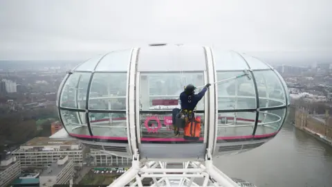 James Manning A window cleaner scrubs the London Eye pods