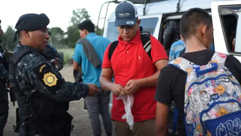 AFP Guatemalan police agents check documents of Hondurans migrants at El Cinchado