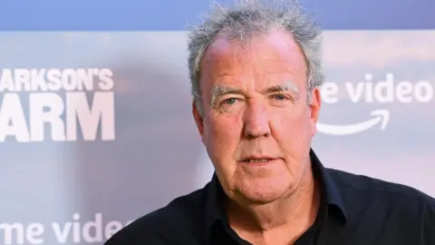 Getty Images Jeremy Clarkson next to publicity sign for Clarkson's Farm