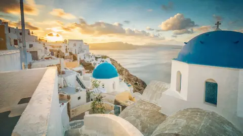 Getty Images Church And Houses In Town By Sea At Santorini During Sunrise - stock photo