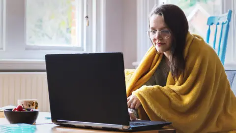 Getty Images Woman home-working with a blanket over her shoulders