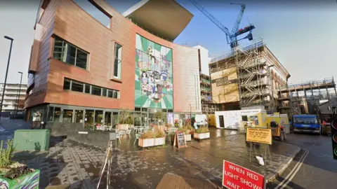 Google Maps Bristol Beacon as it looked in November 2021 with scaffolding and road signs for temporary traffic lights. You can see a mural on the side of the building