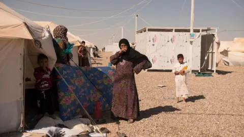 Melany Markham/NRC People from the town of al-Qaim outside their tents in the Kilo 18 camp for displaced people near Ramadi, Iraq (October 2017)