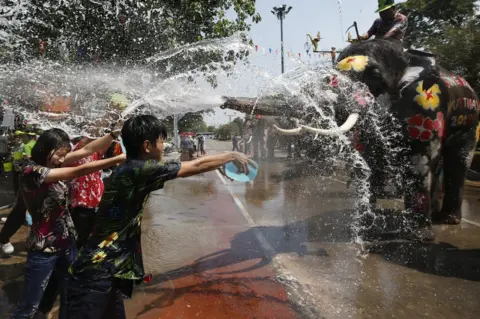 RUNGROJ YONGRIT/ EPA Thai revellers throw water with elephants.