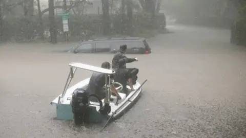 Getty Images Volunteers and officers from a neighbourhood security patrol in Houston help to rescue residents in River Oaks, 27 August 2017