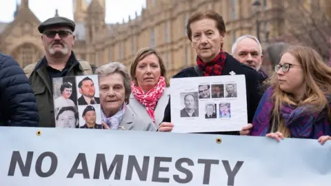 PA Media demonstrators holding photos of their loved ones and a banner that says No Amnesty