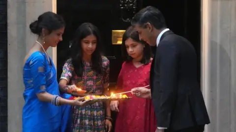 Magnum Photos Rishi Sunak and his wife Akshata Murty with their daughters marking Diwali by lighting the Diyas candle