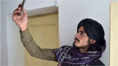 Getty Images A Taliban fighter searches for a network signal for his mobile phone at a hospital.