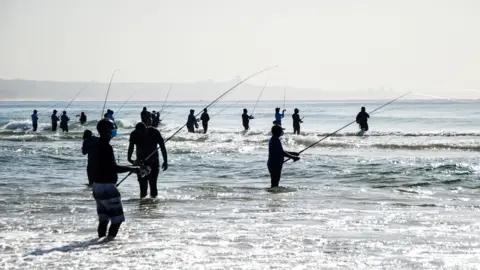 Getty Images Fisherman with rods standing in the sea off Durban, South Africa - Saturday 26 June 2021