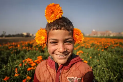 MOHAMED ELSHAHED/GETTY IMAGES A child poses flowers in a field.