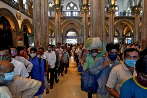 Reuters People wearing protective face masks wait in queues to buy train tickets at the Chhatrapati Shivaji Maharaj Terminus (CSMT) railway station after authorities resumed suburban train services for all commuters after it was shut down to prevent the spread of the coronavirus disease (COVID-19), in Mumbai, India, February 1, 2021.