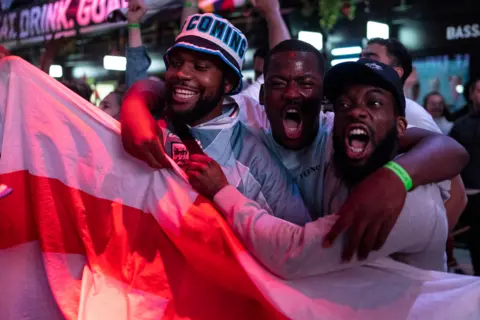 Dan Kitwood / Getty Images England fans cheer at BOXPARK Croydon as they watch a live broadcast of the semi-final match between England and Denmark on 7 July 2021