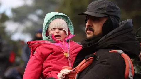 Getty Images A man holds his child on the Poland-Belarus border