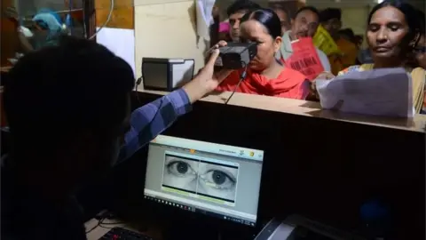 AFP This photo taken on July 17, 2018 shows an Indian woman looking through an optical biometric reader that which scans an individual's iris patterns, during registration for Aadhaar cards (or unique identifier [UID] cards) in Amritsar